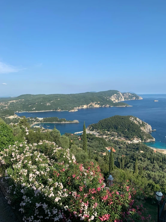 two people are taking pictures on a mountain top overlooking the ocean