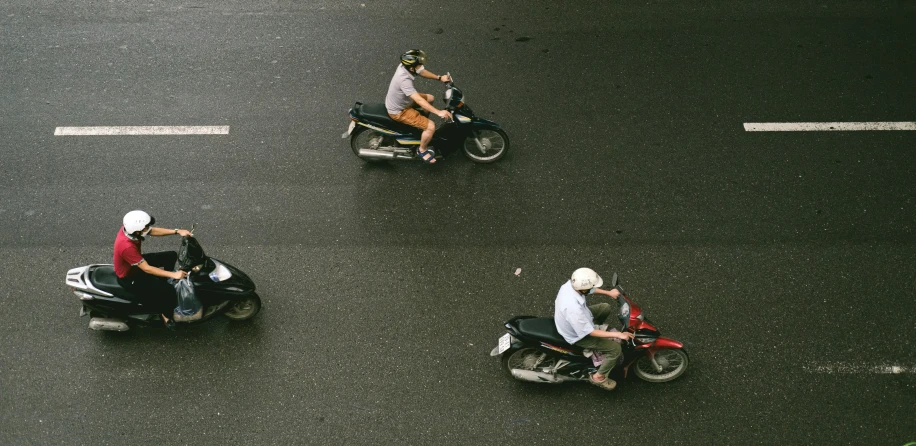 three people on motor bikes in a busy street