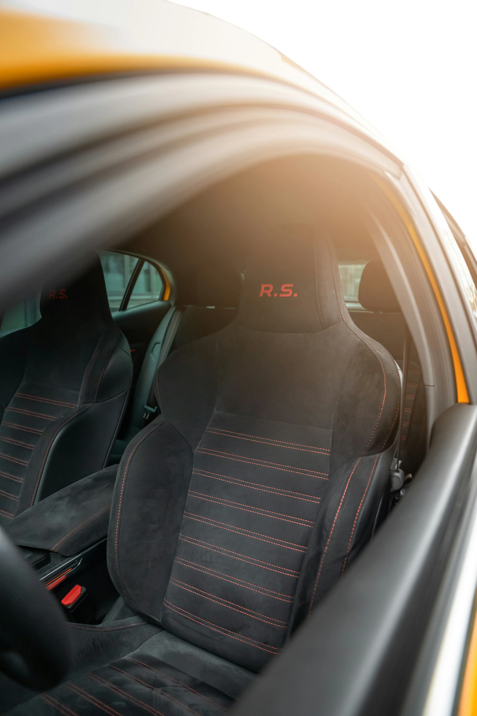 front seats of modern yellow car with red stitching