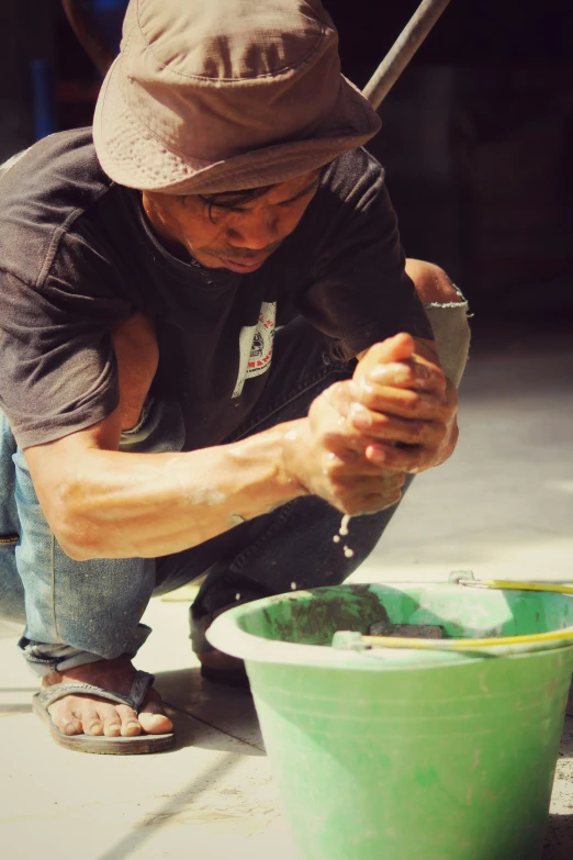 a person is kneeling and working on soing in a green bucket