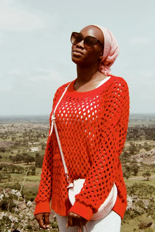 a woman wearing a bright red shirt standing in the middle of a field