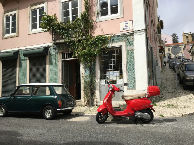 a small red motor scooter parked in front of a building