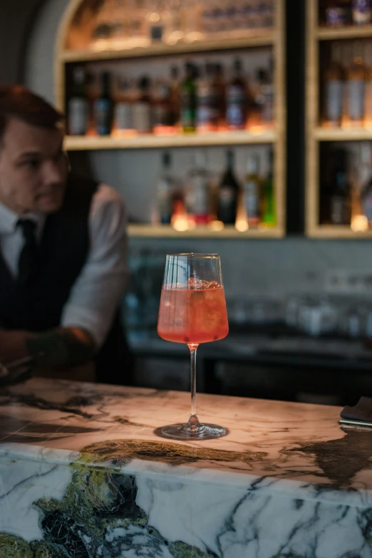 man sitting behind bar in dark room with bottles of alcohol