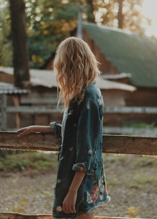 a woman standing at a fence holding a skateboard