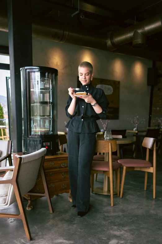 woman in black standing in front of an old fashioned refrigerator