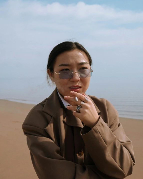 a woman wearing glasses posing on the beach