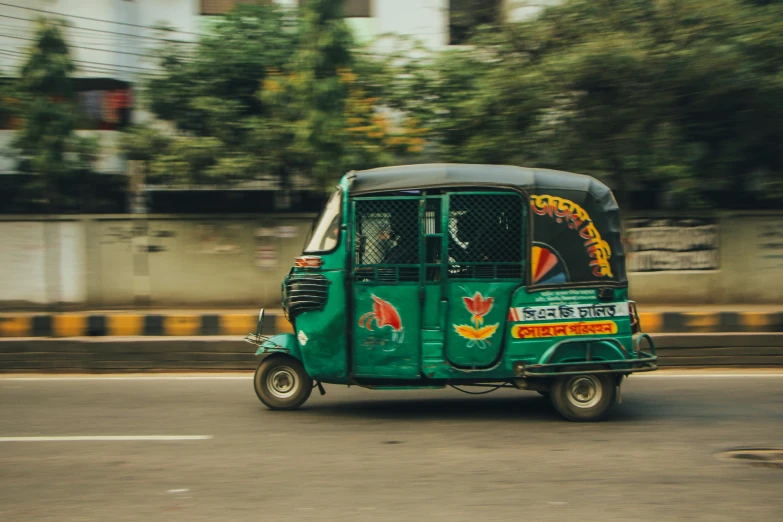 a small green car going down a street