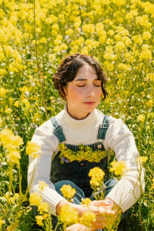 a little girl sits in the middle of a field of yellow flowers