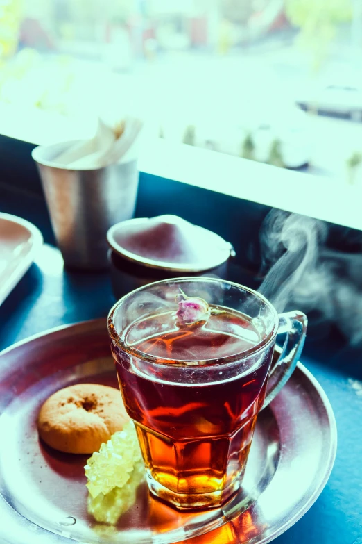 a tea mug, tea, donut and teaspool on a table