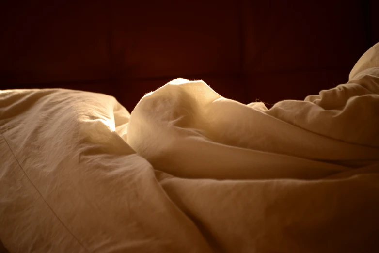 a po of a white bed spread with a brown wall behind it