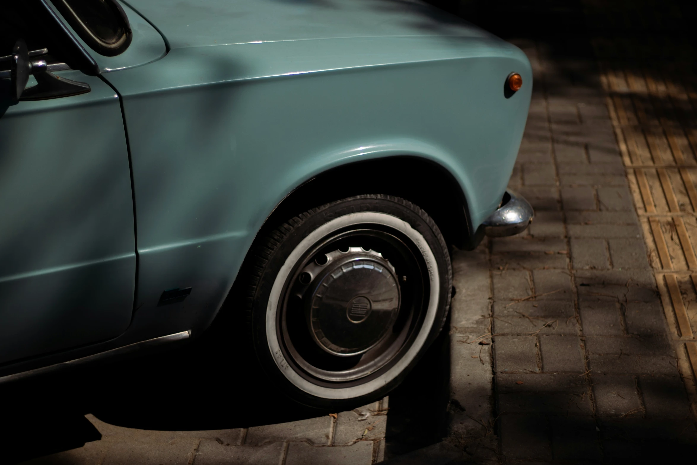 a green vintage automobile parked on the side of the road