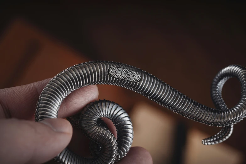 a hand holding silver snakes and a piece of metal