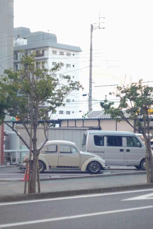 an old beetle is parked beside a white van