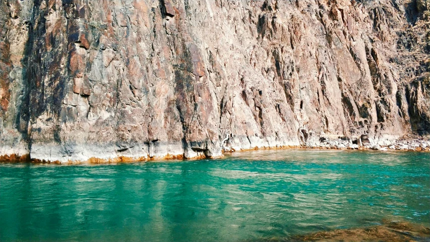 large mountains in the distance along water with green blue water