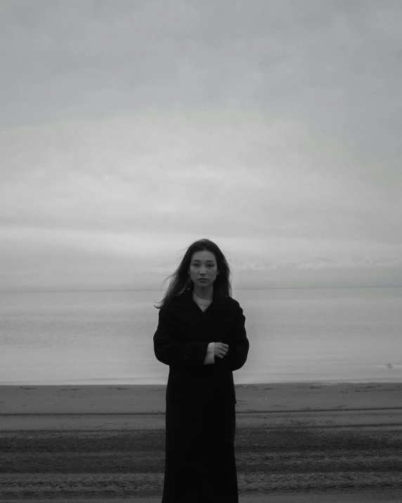 woman standing on sand looking at camera while holding a frisbee