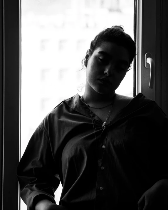 a woman is posing in front of a window