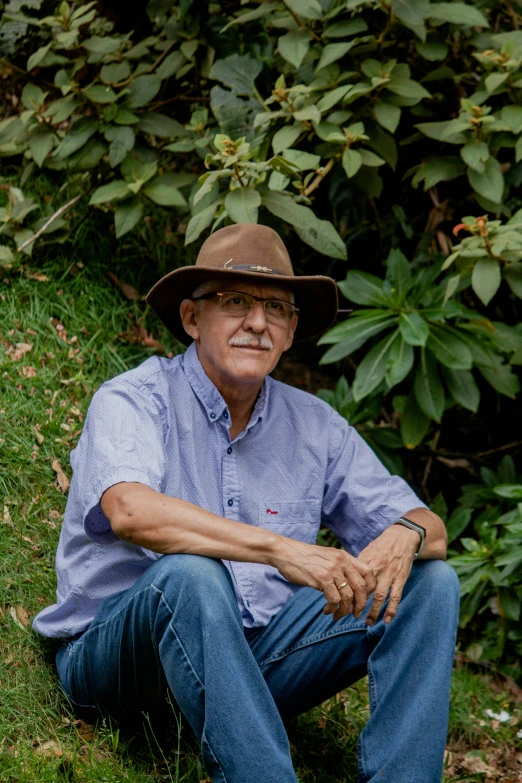 a man sitting in grass wearing a brown hat