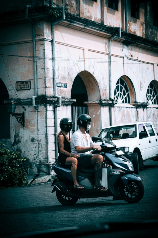 two people are riding on a motor scooter