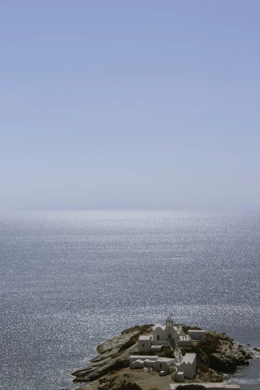 a bird flying over the ocean from an island