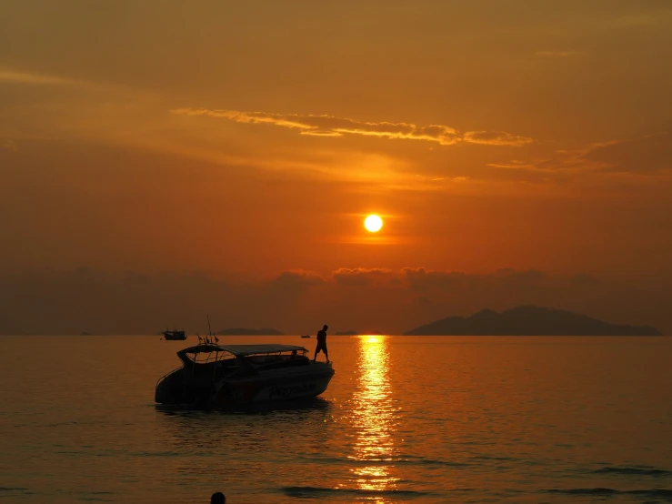 a boat sailing across a lake under the sunset