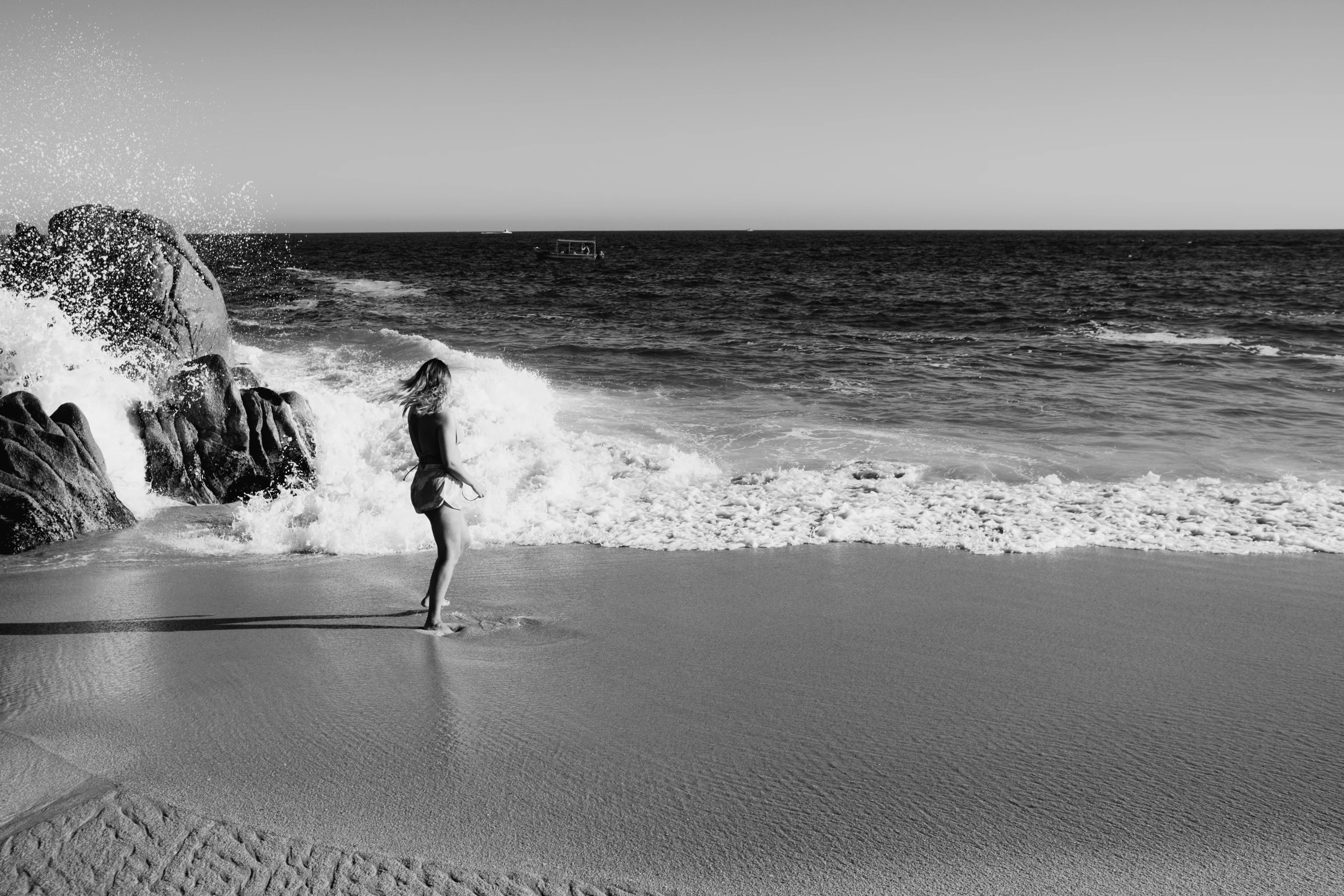 a person stands in the surf next to some rocks