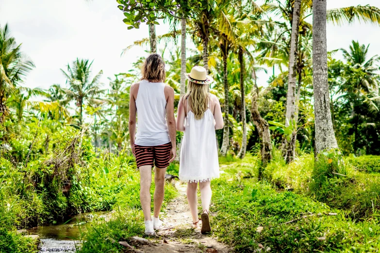 a man and woman are walking along a path in the forest