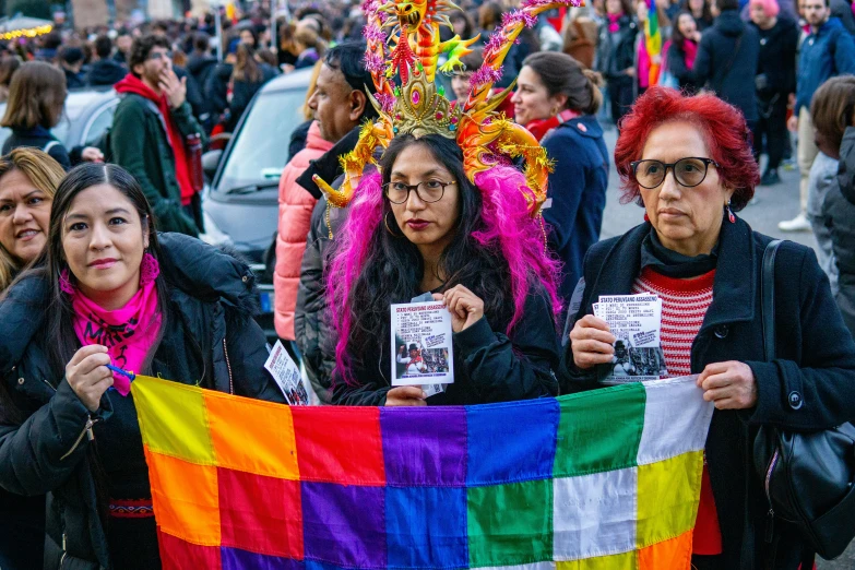 two women holding up a rainbow banner at a pride parade