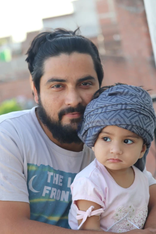 a man with a beard holding a child wearing a head scarf