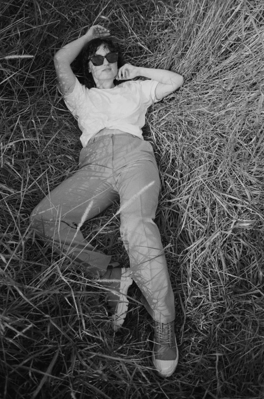 a woman laying on top of a dry grass field