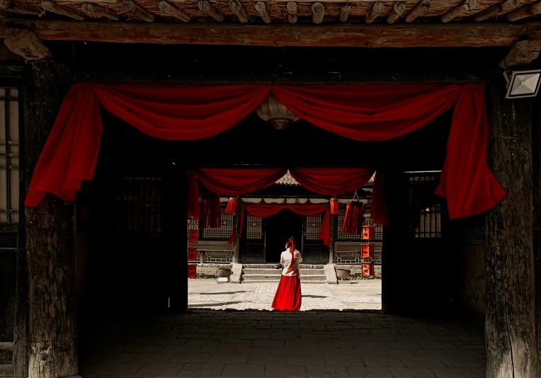 a woman in a red dress is standing under a large tent