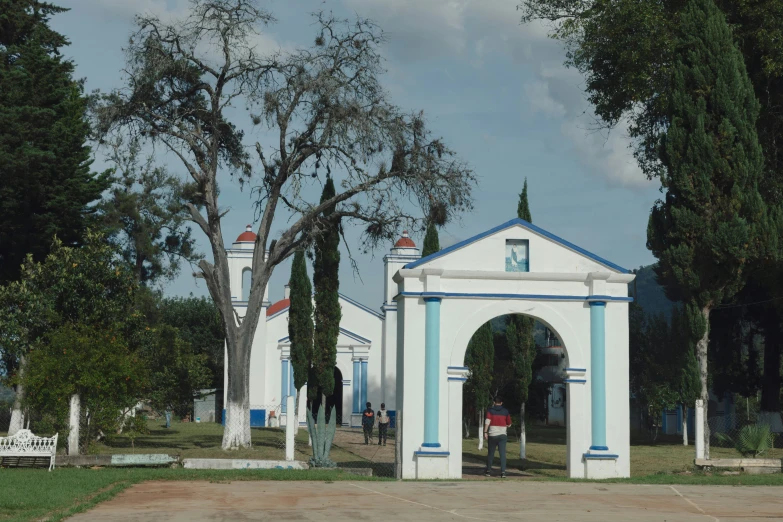 two white buildings sit on a lot surrounded by trees