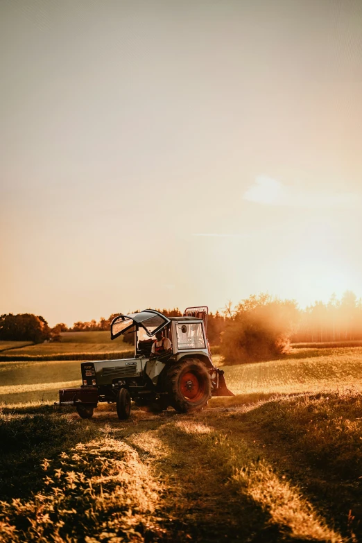 a person is riding on the back of a tractor in the field