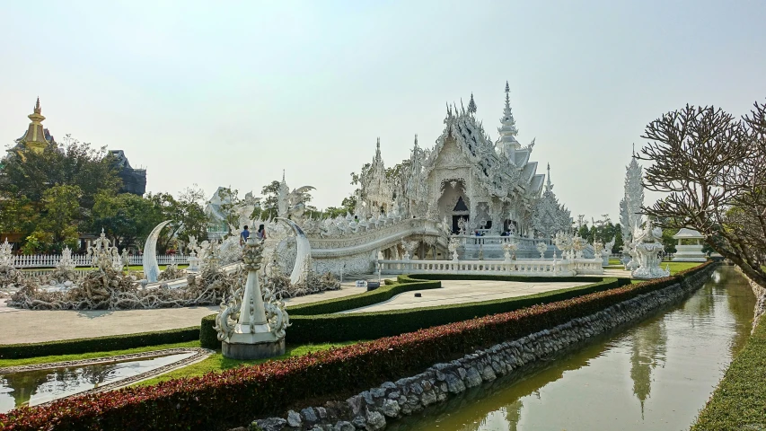 large building on land with flower beds and water