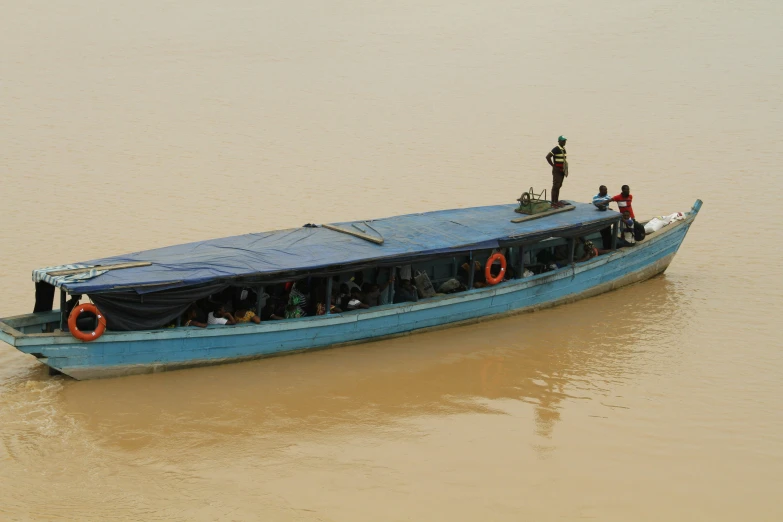 a small boat in the water with a lot of people standing on top of it