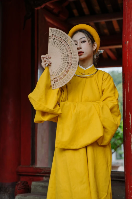 a woman is dressed in bright yellow holding an umbrella
