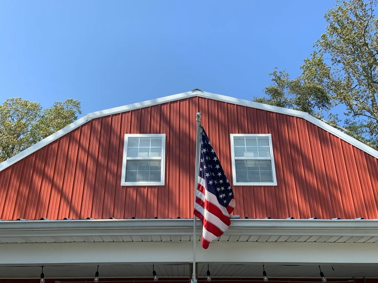 an american flag that is flying next to a red house