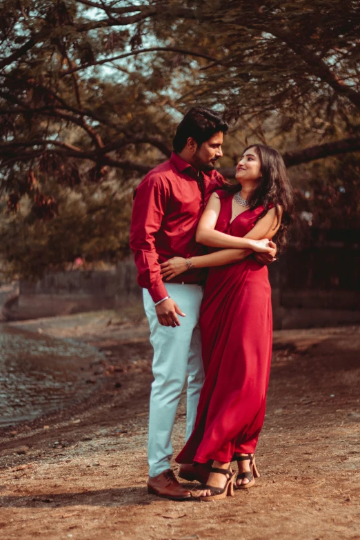 a couple in red are standing outside by the water