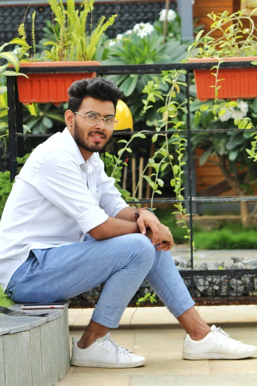 a man wearing white shirt and jeans sitting on a cement block