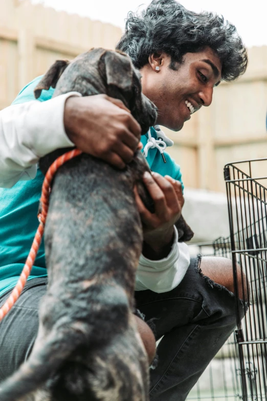 a person hugging their dog near a cage