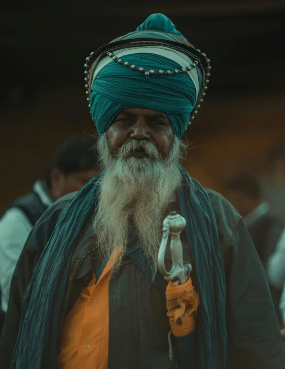 a man with a long beard and green turban, wearing an orange vest and tie