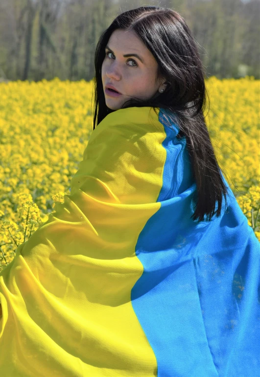 a woman with brown hair in a large yellow field of flowers