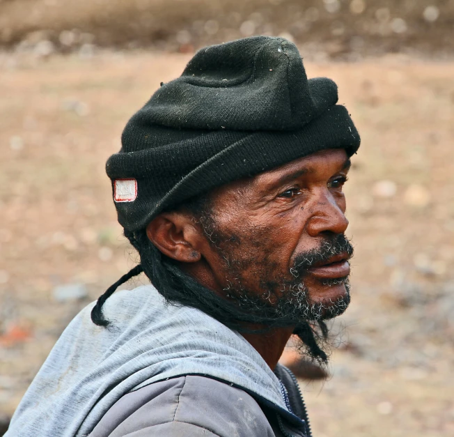 a man with ids and a hat stares ahead