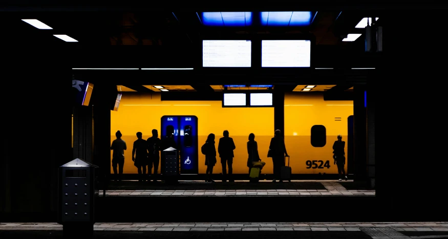 a yellow subway car with people waiting at it