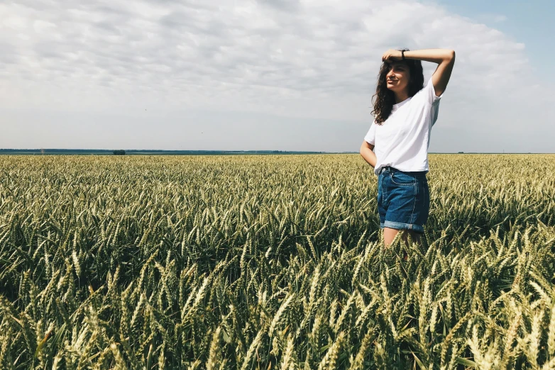 a woman standing in the middle of a wheat field