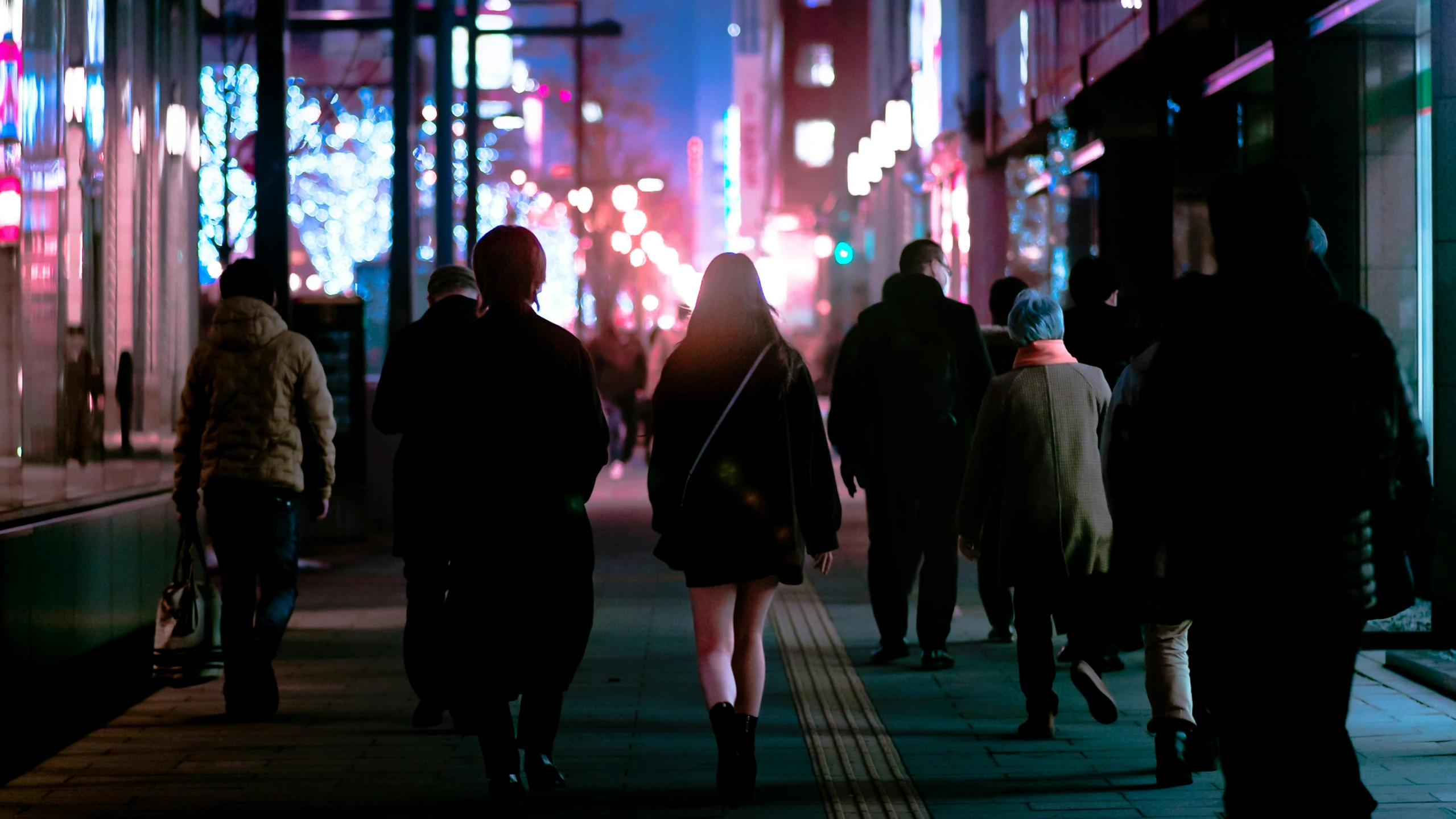 silhouettes of several people walking down a city sidewalk