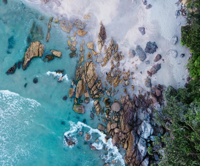 an aerial view shows rocky coastlines and turquoise water