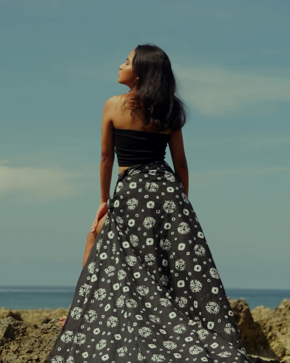 a woman with long dark hair looking off into the distance on a beach