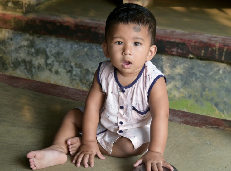 a little baby sitting in front of some stairs