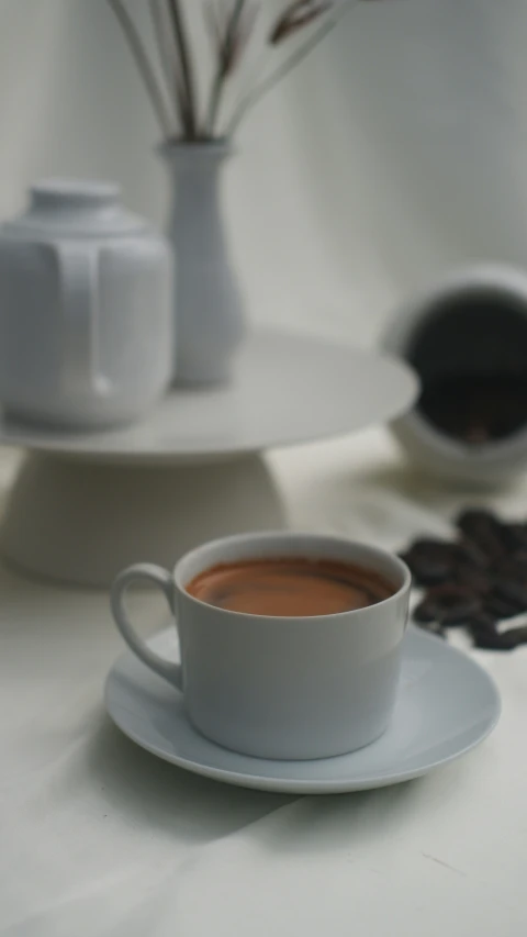 a cup of coffee on a saucer in front of a plate with flowers