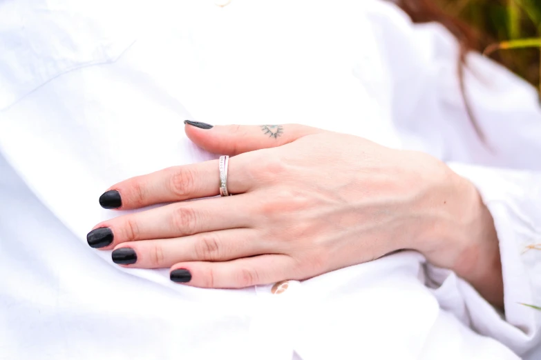 a person holding onto a white shirt and wearing a black manicure